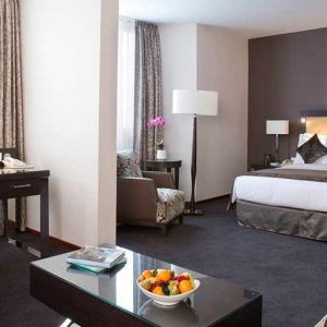 spacious king room with TV, work desk, chair, and couch at DoubleTree by Hilton Luxembourg.