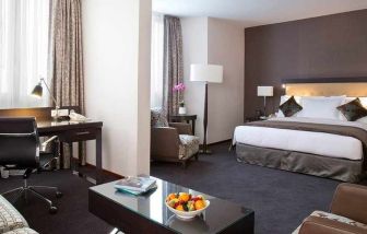 spacious king room with TV, work desk, chair, and couch at DoubleTree by Hilton Luxembourg.