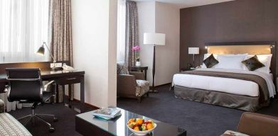 spacious king room with TV, work desk, chair, and couch at DoubleTree by Hilton Luxembourg.