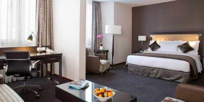 spacious king room with TV, work desk, chair, and couch at DoubleTree by Hilton Luxembourg.