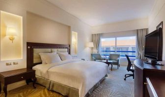 lovely king suite with TV, lounge area, work desk, and chair at Hilton Alexandria Green Plaza.