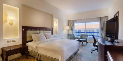 lovely king suite with TV, lounge area, work desk, and chair at Hilton Alexandria Green Plaza.