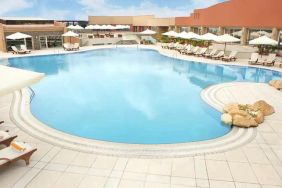 stunning outdoor pool with sunbeds and umbrellas at Hilton Alexandria Green Plaza.