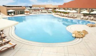 stunning outdoor pool with sunbeds and umbrellas at Hilton Alexandria Green Plaza.