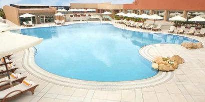 stunning outdoor pool with sunbeds and umbrellas at Hilton Alexandria Green Plaza.