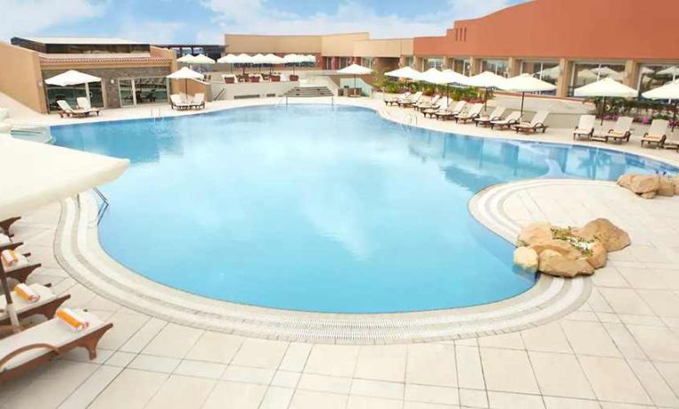 stunning outdoor pool with sunbeds and umbrellas at Hilton Alexandria Green Plaza.