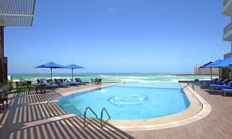 stunning outdoor pool with sunbeds and umbrellas at Hilton Alexandria Corniche.