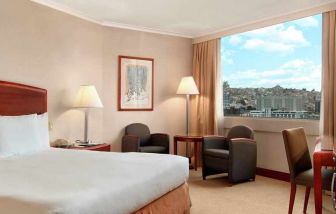 comfortable king room with TV, desk, chair, and couches at Hilton Colon Quito.