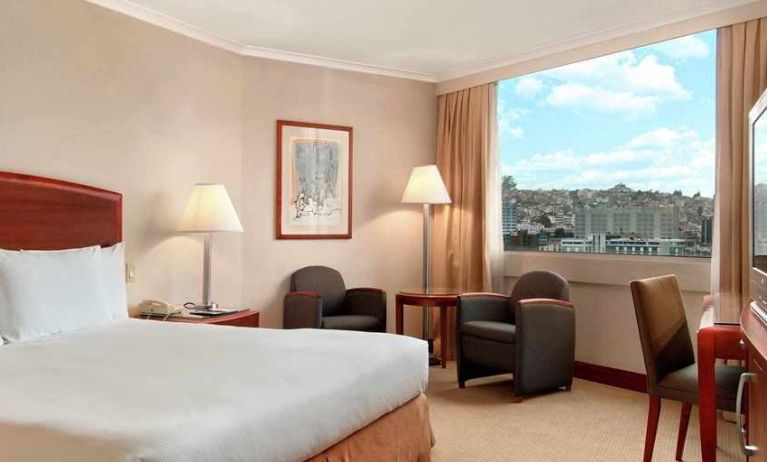 comfortable king room with TV, desk, chair, and couches at Hilton Colon Quito.