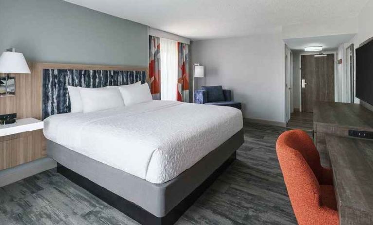 bright-lit king-sized bed in a spacious room with work desk at Hampton Inn & Suites Tampa-Ybor City/Downtown.