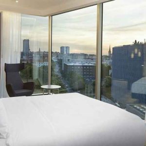 delux king bed with chair and city views at Hilton Tallinn Park.