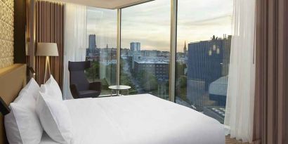 delux king bed with chair and city views at Hilton Tallinn Park.