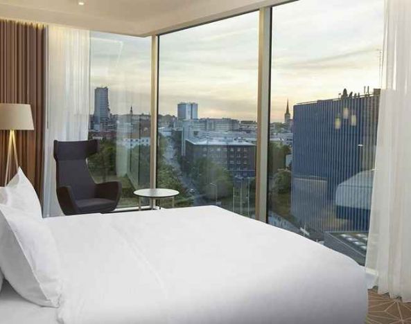 delux king bed with chair and city views at Hilton Tallinn Park.