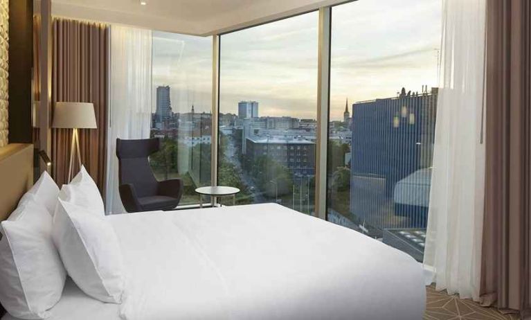 delux king bed with chair and city views at Hilton Tallinn Park.