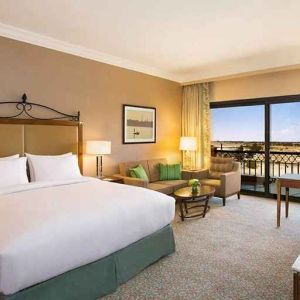 spacious delux king bedroom with TV, desk, chair, and lounge area at Hilton Alexandria King's Ranch.