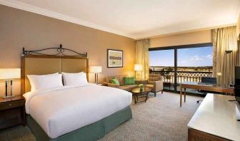 spacious delux king bedroom with TV, desk, chair, and lounge area at Hilton Alexandria King's Ranch.