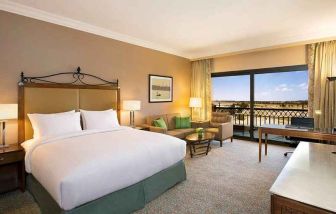 spacious delux king bedroom with TV, desk, chair, and lounge area at Hilton Alexandria King's Ranch.