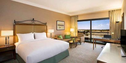 spacious delux king bedroom with TV, desk, chair, and lounge area at Hilton Alexandria King's Ranch.