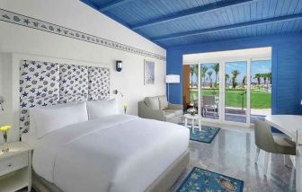 spacious king suite with desk, chair, couch, and outdoor terrace at Hilton Hurghada Plaza.