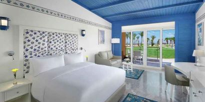 spacious king suite with desk, chair, couch, and outdoor terrace at Hilton Hurghada Plaza.