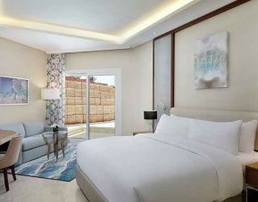 comfortable delux king room with TV, desk, chair, and couch at Hilton Hurghada Plaza.