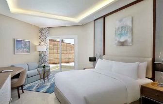 comfortable delux king room with TV, desk, chair, and couch at Hilton Hurghada Plaza.