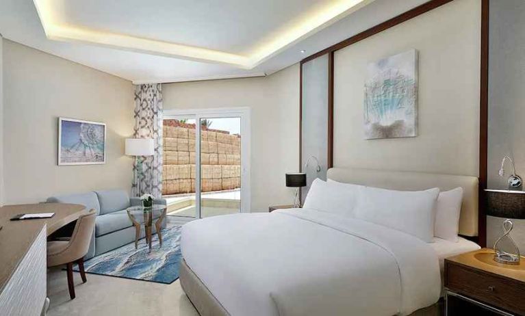 comfortable delux king room with TV, desk, chair, and couch at Hilton Hurghada Plaza.