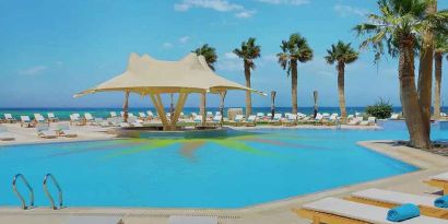 stunning outdoor pool with sunbeds and umbrellas at Hilton Hurghada Plaza.