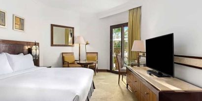 spacious king suite with TV, desk, chair, and dining area at Hilton Luxor Resort & Spa.