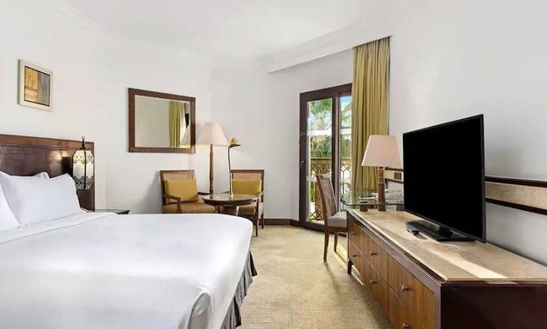 spacious king suite with TV, desk, chair, and dining area at Hilton Luxor Resort & Spa.