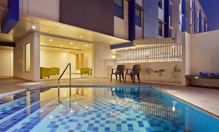 lovely outdoor pool with seating area at Hampton by Hilton Vadodara-Alkapuri.