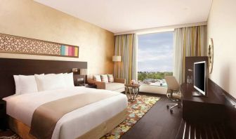 Spacious executive day room with floor-to-ceiling window, large desk, television, king bed at the Hilton Jaipur.