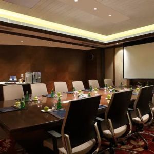 Sleek boardroom with large projection screen, seating for up to 12-15 people.