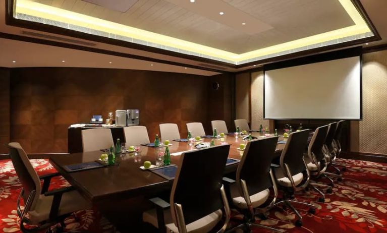 Sleek boardroom with large projection screen, seating for up to 12-15 people.