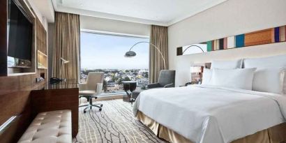 spacious king suite with TV, business desk, lounge area, and city views at Hilton Chennai.