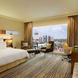 comfortable delux king room with TV, business desk, and lounge area at Hilton Chennai.