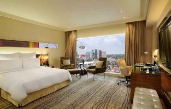 comfortable delux king room with TV, business desk, and lounge area at Hilton Chennai.