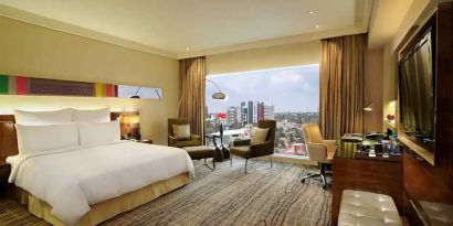 comfortable delux king room with TV, business desk, and lounge area at Hilton Chennai.