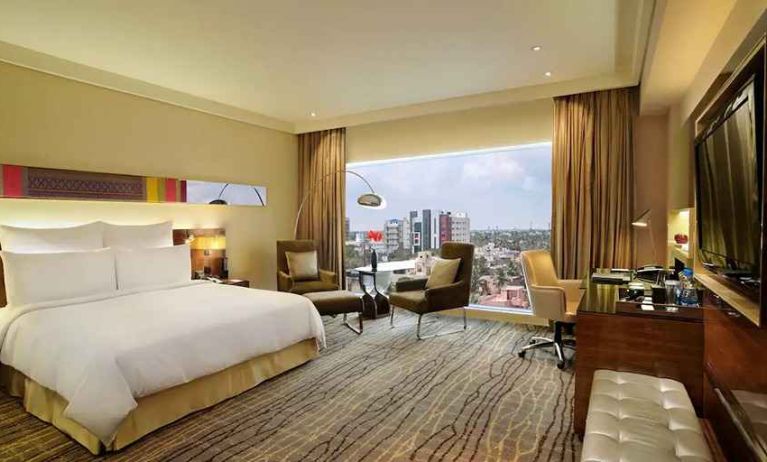 comfortable delux king room with TV, business desk, and lounge area at Hilton Chennai.