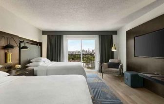 Double queen room with TV screen at the Embassy Suites by Hilton Los Angeles Downey.