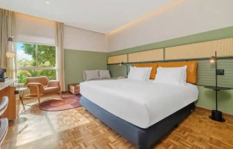 Large suite with king-size bed, bright window view, sequenced wood flooring, seating area.