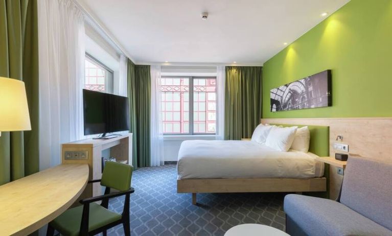 Lime green walls and a chic city view complement this king-size bed with workspace and television hotel room.