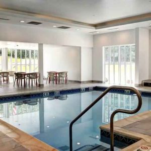 Small rectangular indoor pool with a few circular tables and chairs alongside.