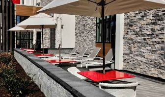 Gray sun layout chairs complement red square tables with chairs on a beautiful outdoor patio at the Hilton Garden Inn Bel Air.