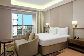 Bright king bedroom with sofa at the DoubleTree Suites by Hilton Bangalore.