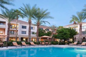 Stunning outdoor pool with sunbeds and pool umbrellas at Sonesta Select Phoenix Chandler.