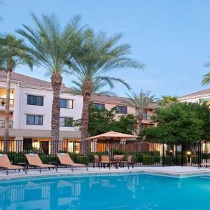 Stunning outdoor pool with sunbeds and pool umbrellas at Sonesta Select Phoenix Chandler.