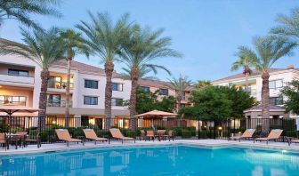 Stunning outdoor pool with sunbeds and pool umbrellas at Sonesta Select Phoenix Chandler.