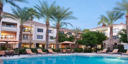 Stunning outdoor pool with sunbeds and pool umbrellas at Sonesta Select Phoenix Chandler.