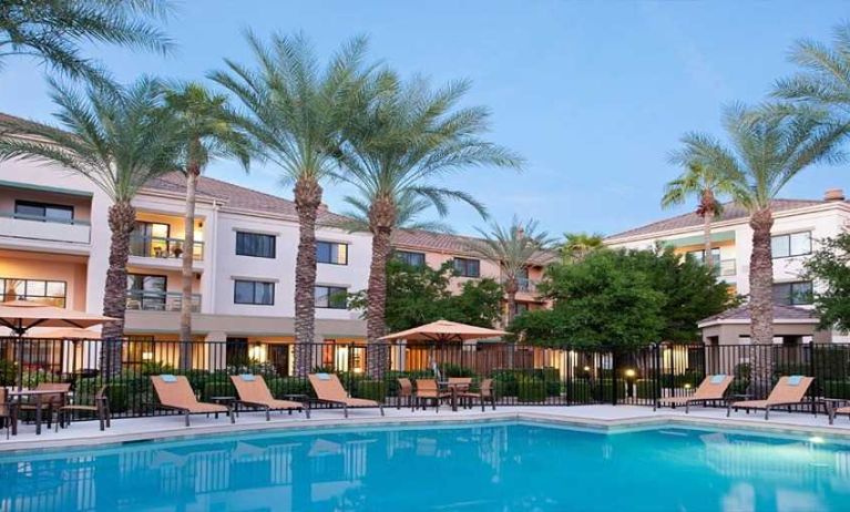 Stunning outdoor pool with sunbeds and pool umbrellas at Sonesta Select Phoenix Chandler.